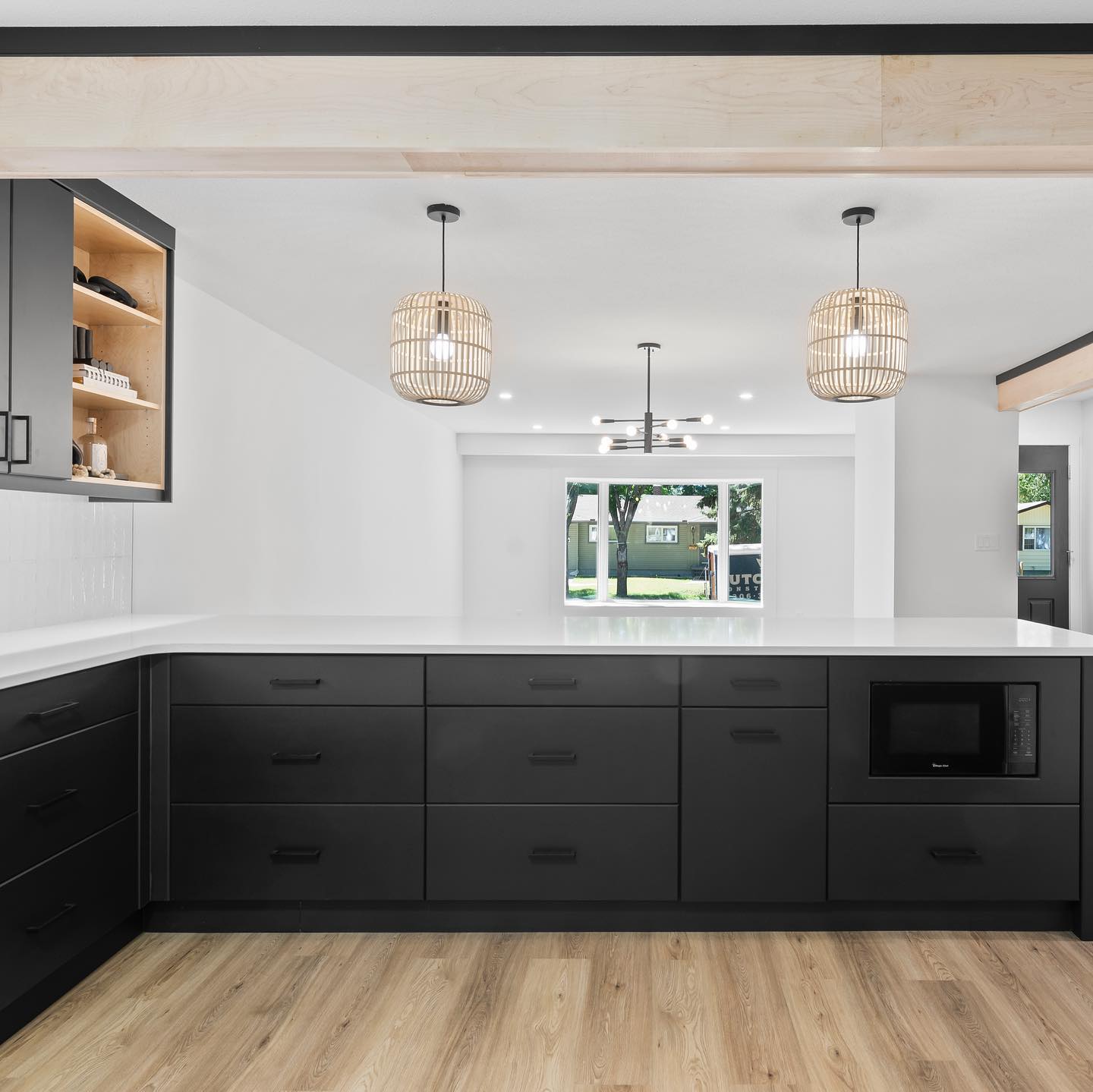 Completed kitchen with black cabinetry, wood accents, and pendant lights